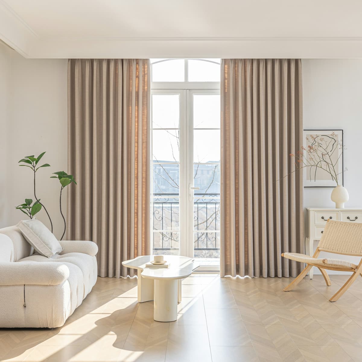 Svetla dnevna soba apartmaja v jutranjem soncu, z lanenimi zavesami in lesenim podom.